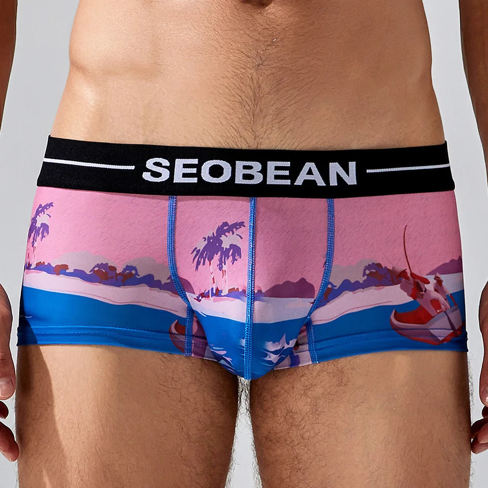 Front view of a model wearing pink and blue tropical-print boxer briefs