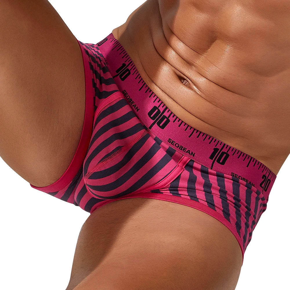 Close-up of a model wearing pink and black striped boxer briefs with a numbered waistband