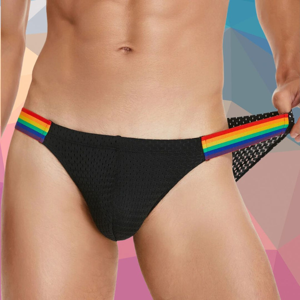 Front close-up of a model wearing black mesh low-rise briefs with rainbow-striped side bands
