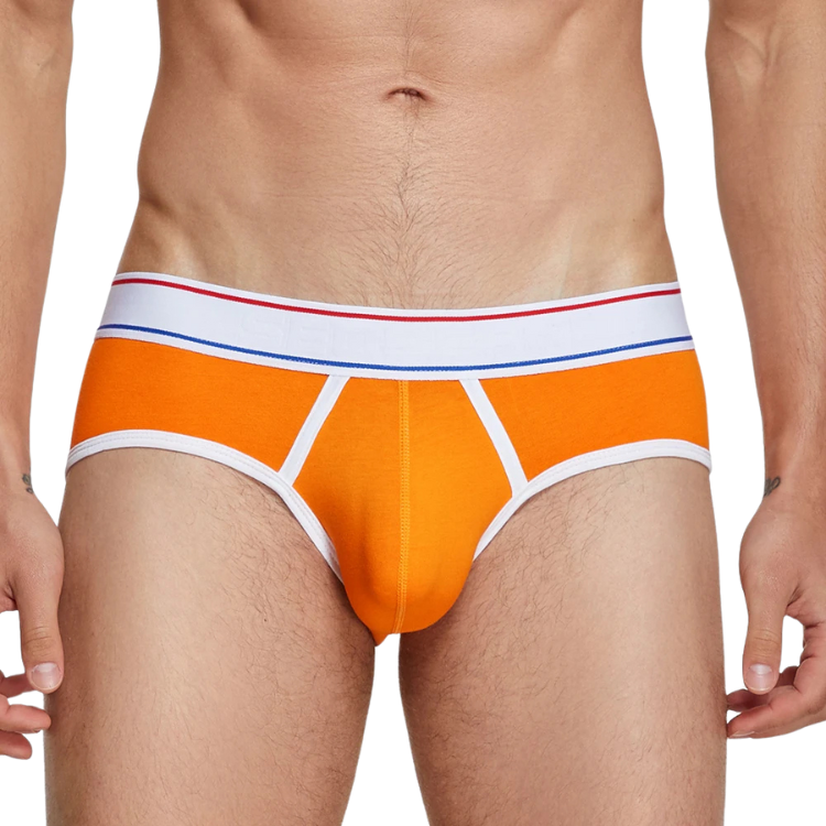 Front view of a model wearing orange men's briefs with white trim and striped waistband