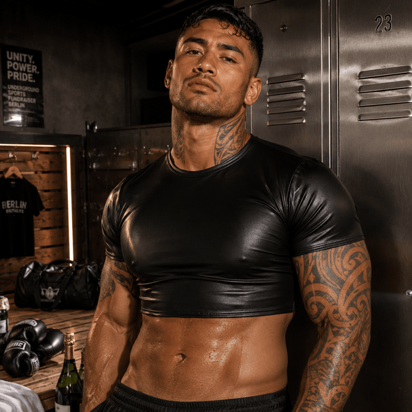Front-facing model wearing a black glossy short-sleeve crop top in a locker room