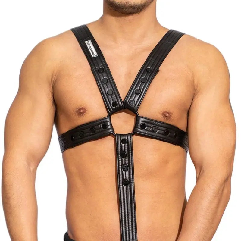 Front view of a shirtless model wearing a black faux-leather chest harness with a central ring