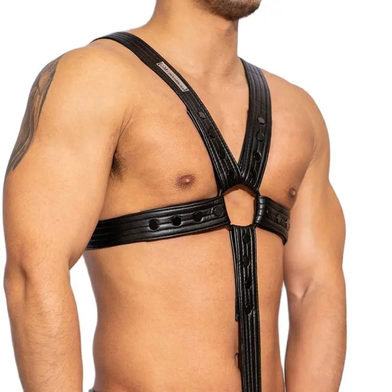 Cropped model wearing a black faux-leather chest harness with adjustable straps