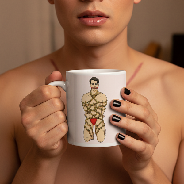 Person holds a white mug showing an illustrated person in a rope harness and red briefs