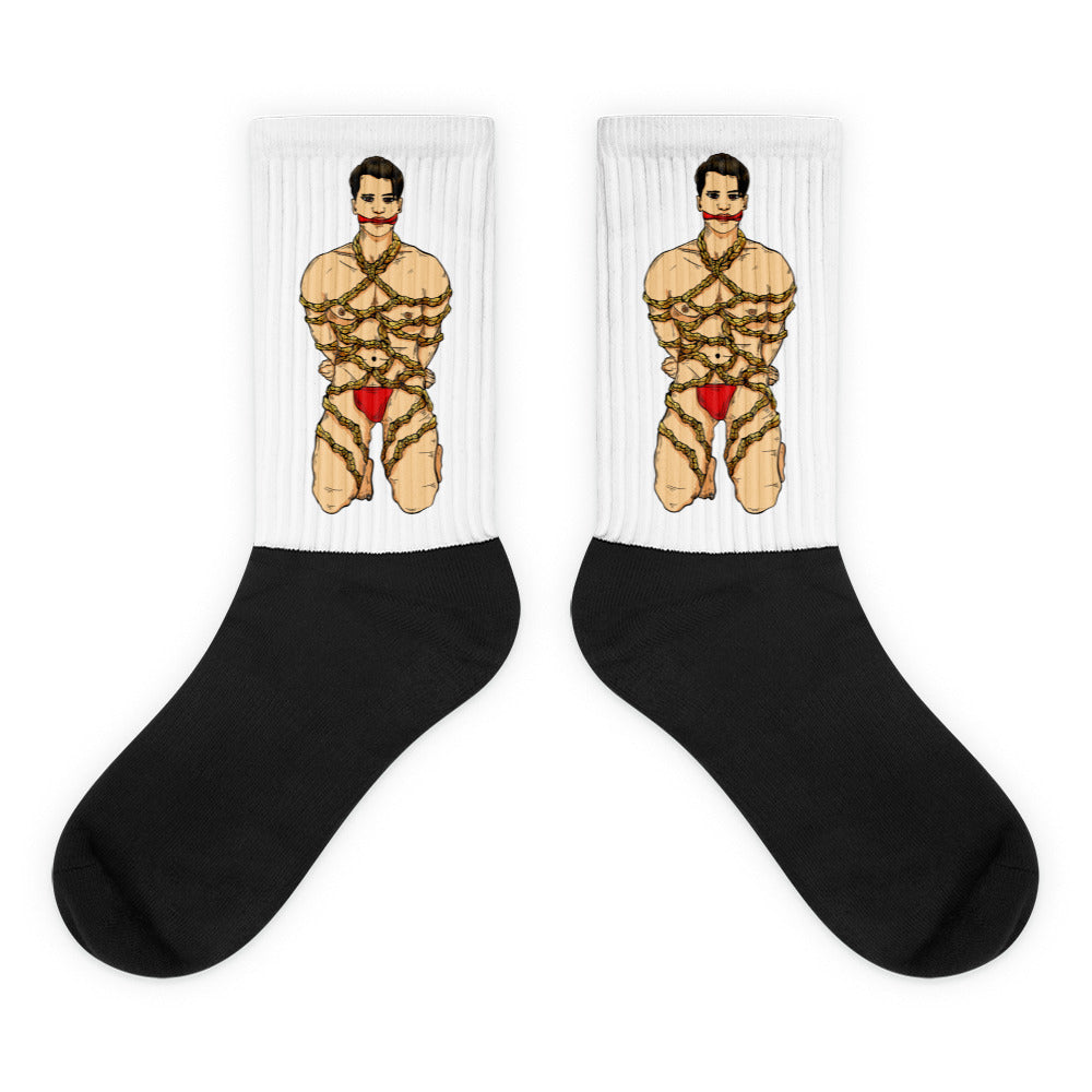 Pair of crew socks with black feet and white legs printed with a bound man in red underwear