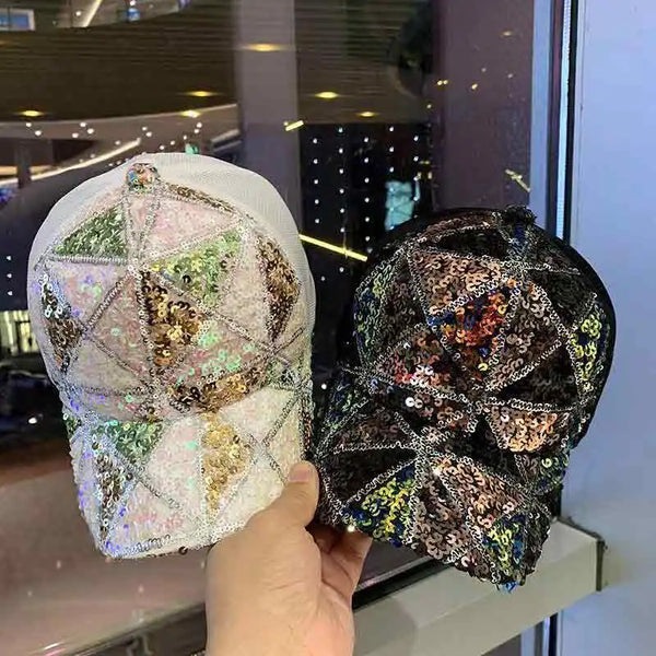 Hand holding two sequin baseball caps, one iridescent white and one black