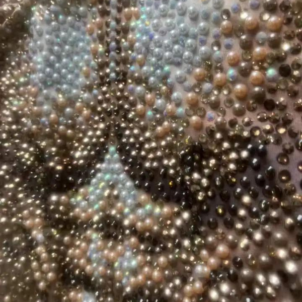 Close-up of a multicolored pearl-studded fabric with silver, black, and bronze beads