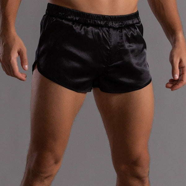 Front view of a model wearing glossy black satin-style short shorts