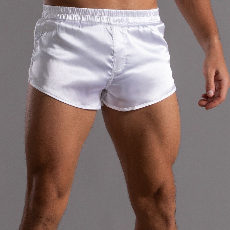 Front view of a model wearing shiny white satin short shorts with an elastic waistband