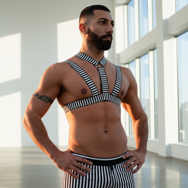 Front three-quarter view of a shirtless person wearing a black-and-white striped chest harness and shorts