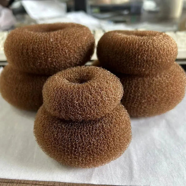 Close-up of four brown mesh donut hair bun makers stacked on a white surface