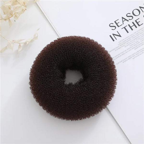 Top view of a dark brown textured foam hair bun donut on a magazine page