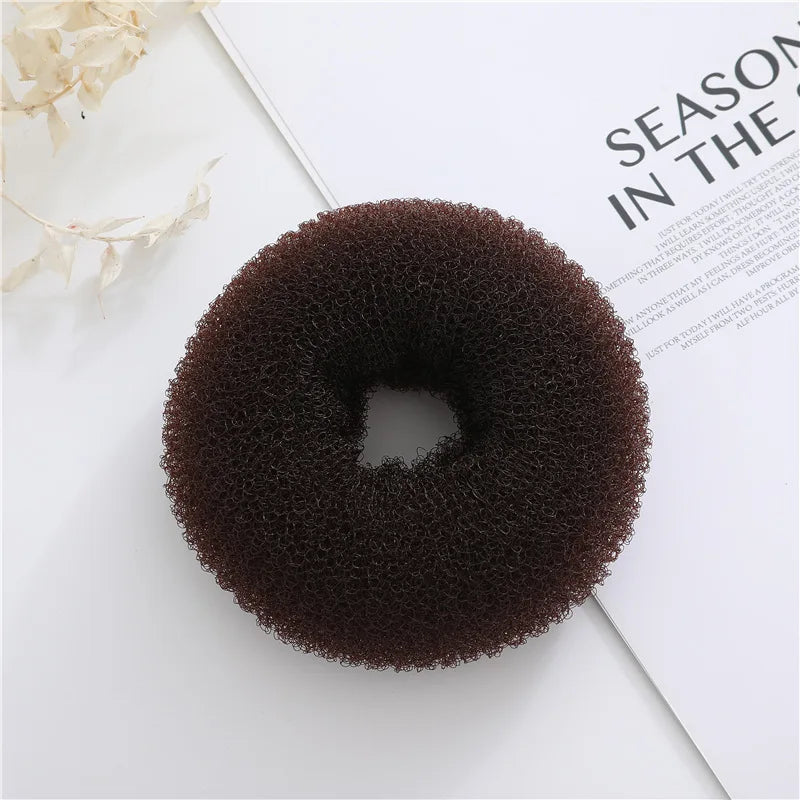 Top view of a dark brown textured foam hair bun donut on a magazine page