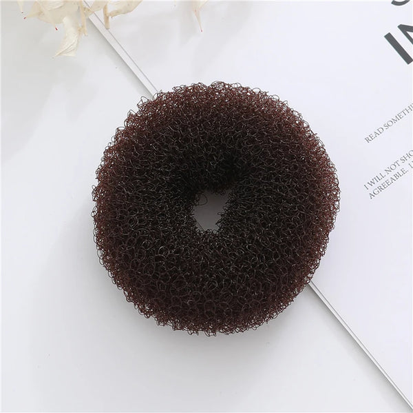 Top view of a dark brown, textured mesh donut bun maker on an open book