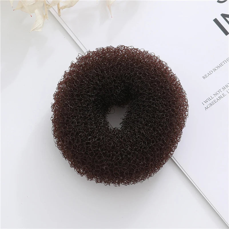 Top view of a dark brown, textured mesh donut bun maker on an open book
