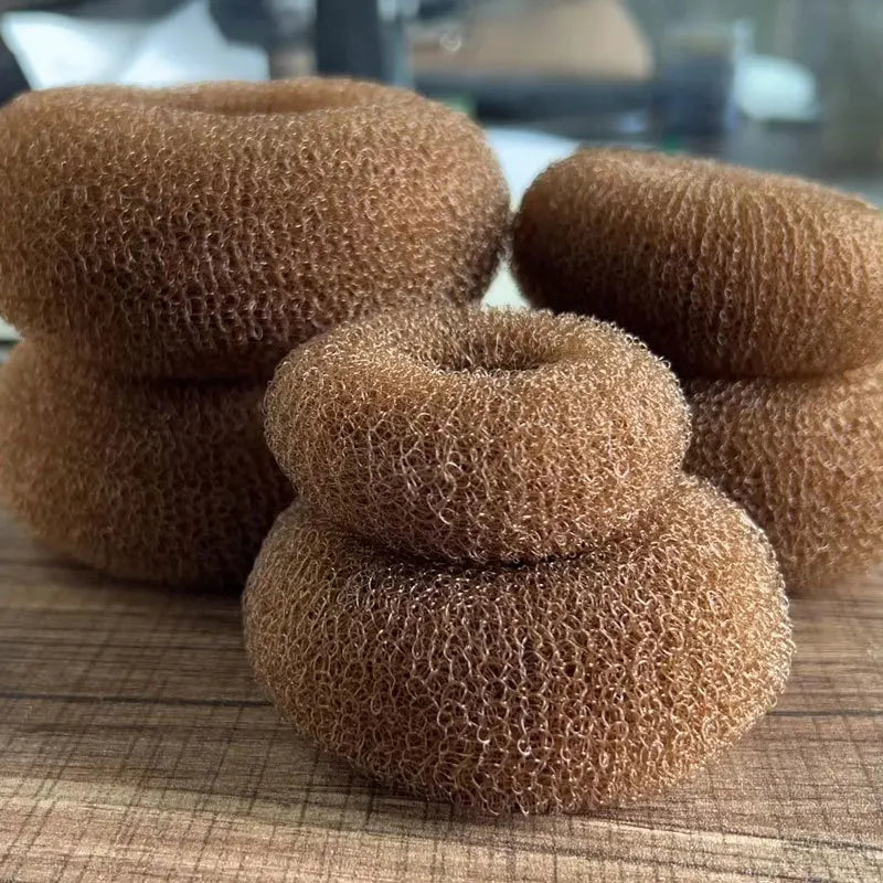 Close-up of several brown donut-shaped bun makers stacked on a wooden surface
