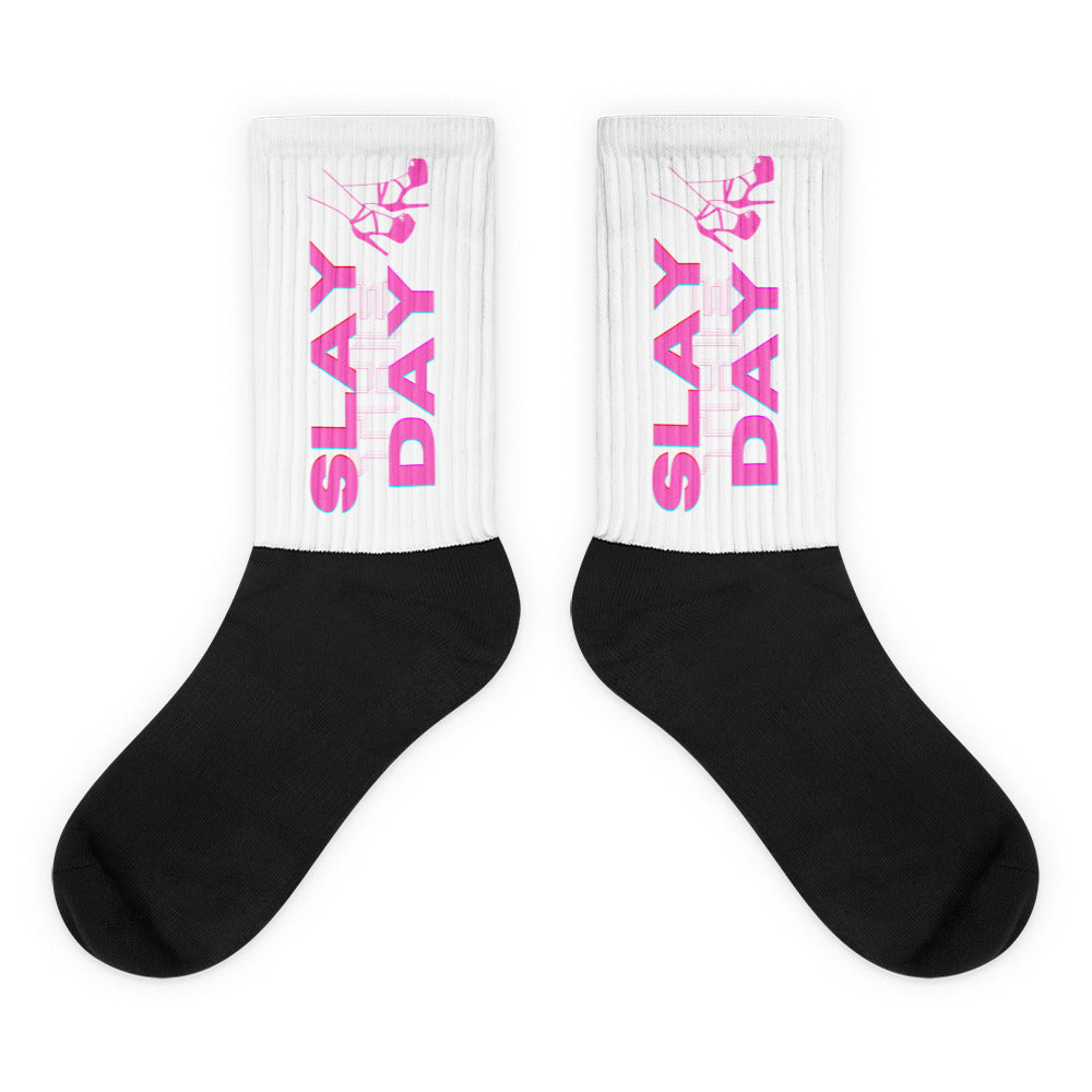 Pair of black-and-white socks with pink “SLAY DAY” lettering and dancing figure