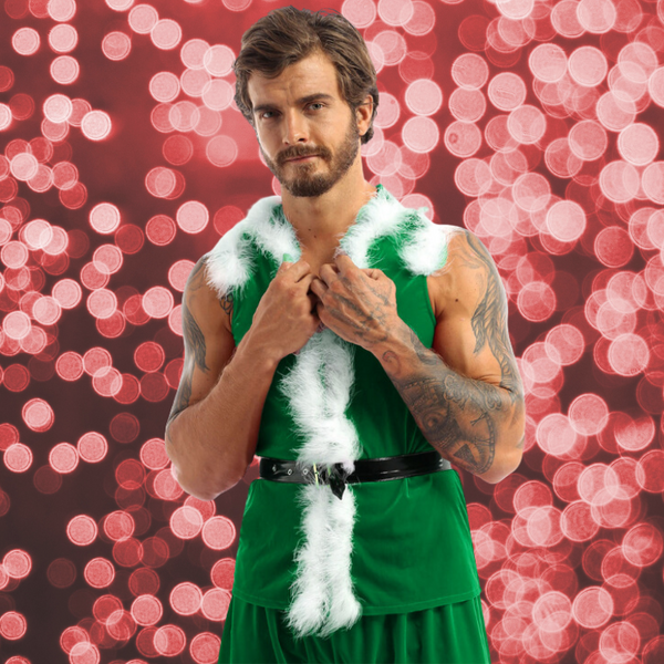 Bearded person models a green sleeveless holiday tunic with white faux-fur trim and black belt