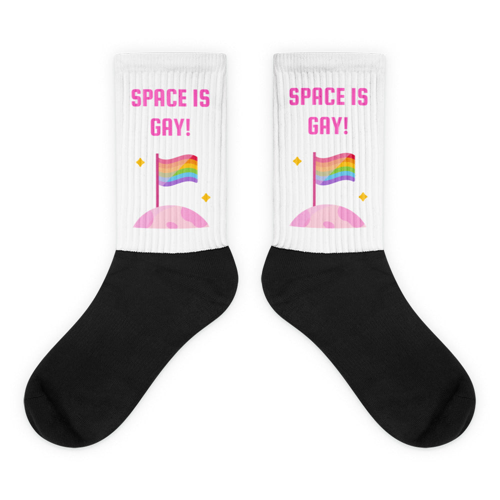 Pair of black-and-white socks reading “SPACE IS GAY!” with rainbow flags and pink planets
