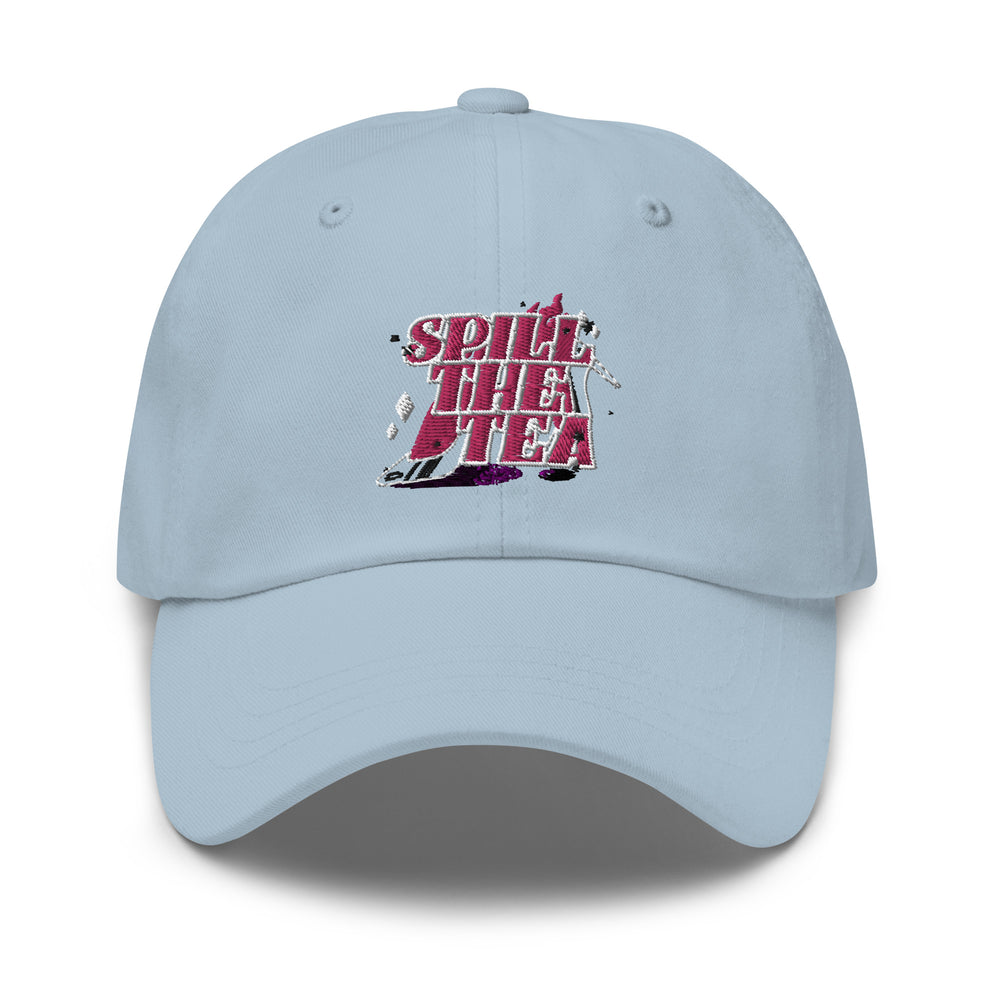 A light-blue, six-panel Spill The Tea Cap with pink and white embroidered text and a tea puddle detail