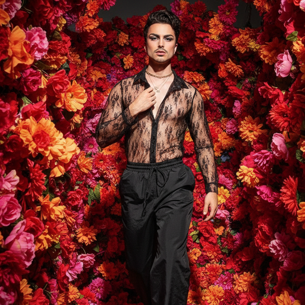Front-view model wearing a sheer black lace shirt among vivid red and orange flowers