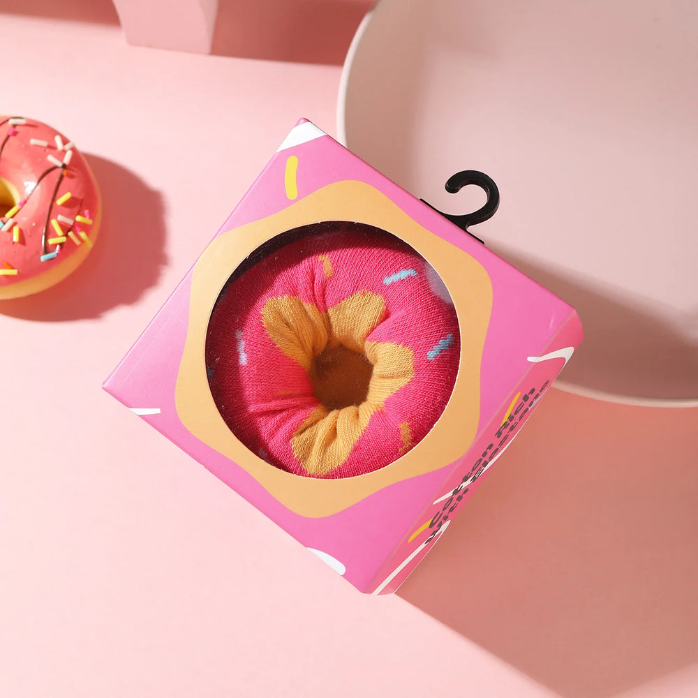 Packaged donut-pattern sock shown through a round window in a pink box