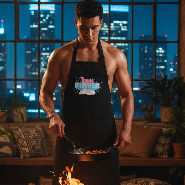 A person cooks in a loft, wearing the Stand Proud Organic Cotton Apron with Trans Power text