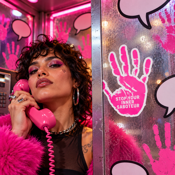 Stop Your Inner Saboteur pink handprint sticker in a surreal neon queer hotline booth