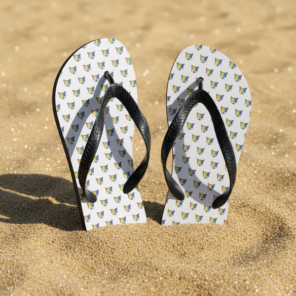 Rainbow Fox Flip-Flops with black straps, covered in a bold, colorful fox face print, standing upright in golden beach sand.
