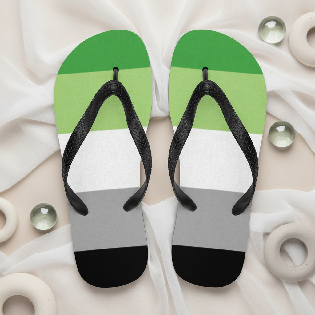 Aromantic Pride flip-flops with black straps, rubber soles striped in green, white, gray, and black; circled by marbles and rings.