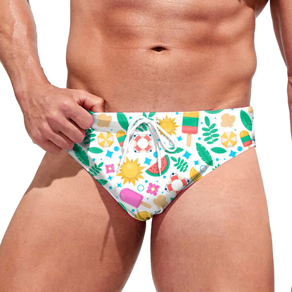 Front view of a person wearing white swim briefs with colorful summer-themed prints and drawstring
