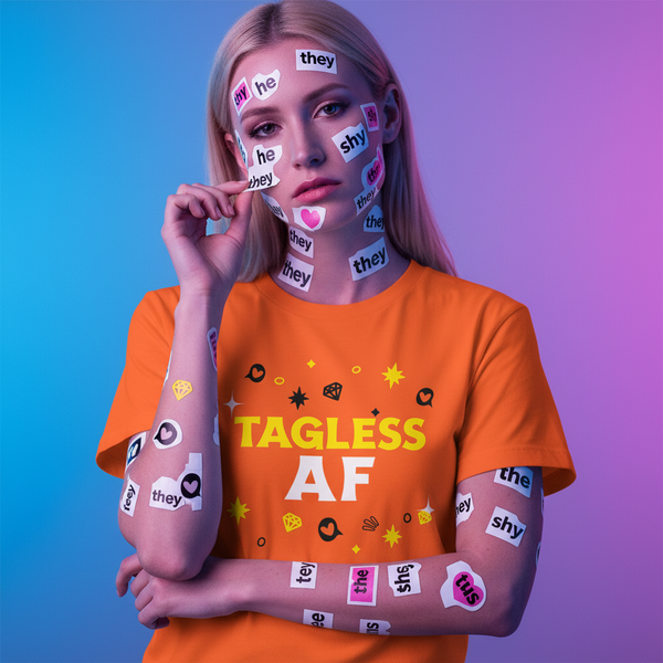 Front-facing person in an orange T-shirt reading “TAGLESS AF,” with pronoun stickers on their face and arms