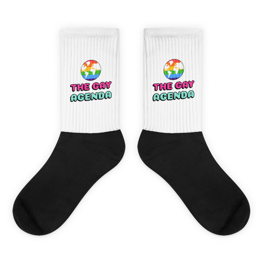 Pair of black-and-white socks reading “THE GAY AGENDA” with rainbow globe graphics