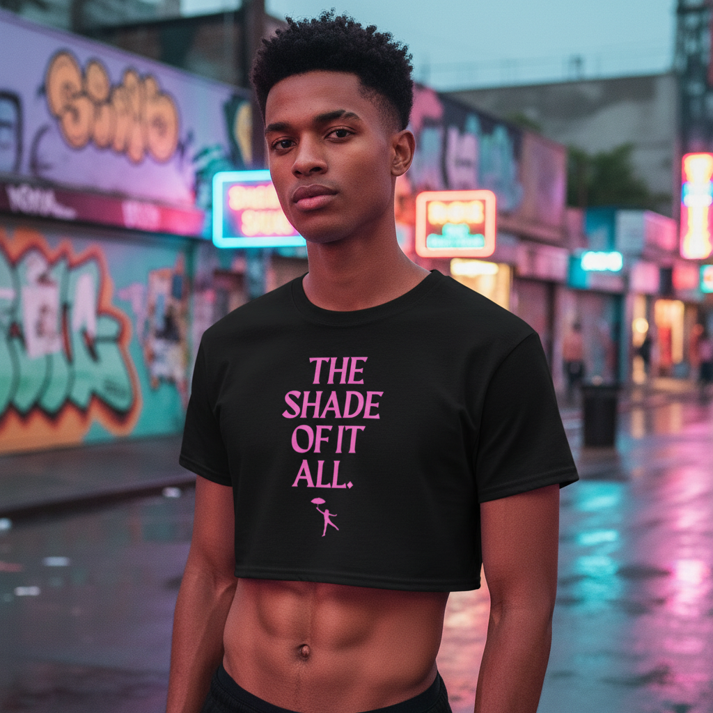 The Shade Of It All black crop top with bold pink text pops on a person at dusk, neon city lights reflecting off wet streets