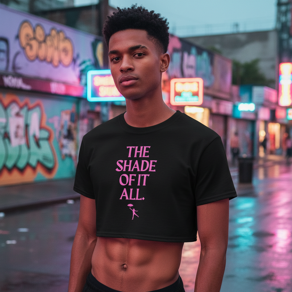 The Shade Of It All black crop top with bold pink text pops on a person at dusk, neon city lights reflecting off wet streets