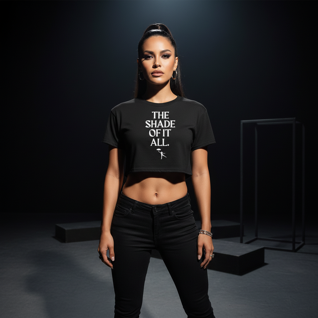 Black relaxed-fit “The Shade Of It All” crop top with bold white text, worn by a confident person in a dark