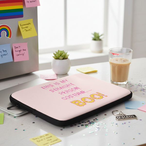 Pink laptop sleeve with “This Is My Straight Person...Boo!” slogan on a desk amid iced coffee, U-HAUL keychain