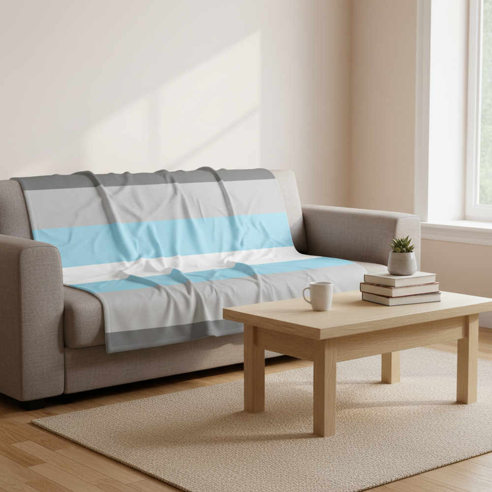 Demiboy Flag Throw Blanket with blue, pink, and white stripes on a light gray sofa; coffee table, books, plant on beige rug.