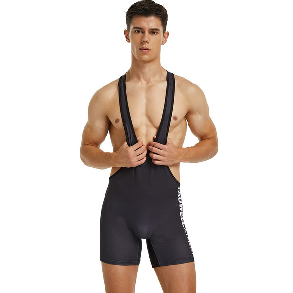 Front-facing model wearing a black wrestling-style bodysuit with wide shoulder straps