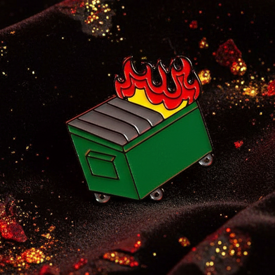 Green dumpster fire enamel pin with red flames and silver wheels