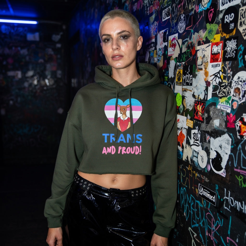 Trans And Proud Crop Hoodie with Scooby-Doo on a trans pride heart and “TRANS AND PROUD!”; queer person in graffiti hallway.