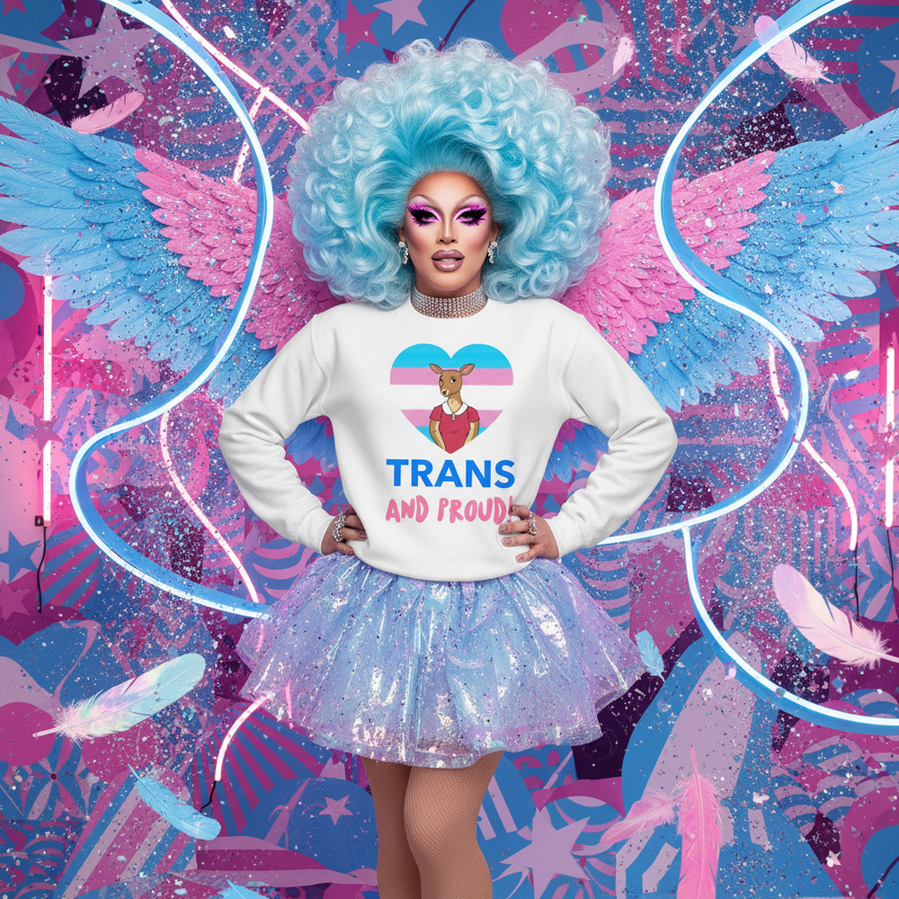 Person in blue wig wearing a white sweatshirt reading “TRANS AND PROUD” with a flag heart graphic