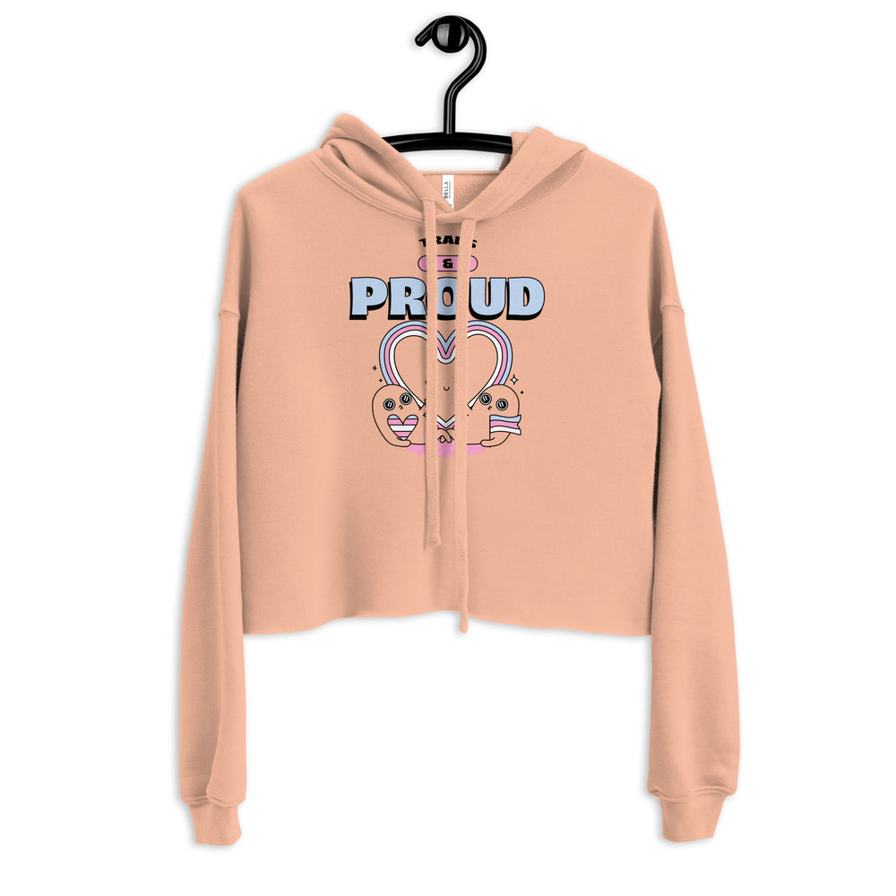Cropped peach hoodie with TRANS & PROUD text and smiling characters forming a heart, celebrating transgender pride.