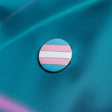 Round transgender Pride enamel pin with pink, blue, and white horizontal stripes