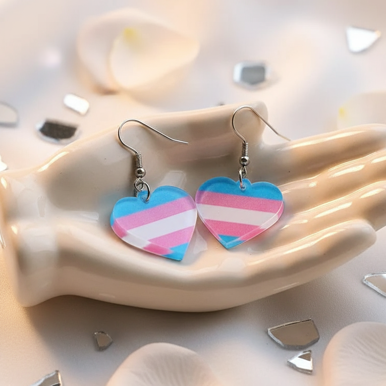 Pair of transgender-flag heart dangle earrings in a hand-shaped dish