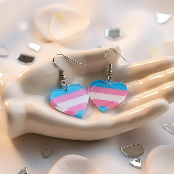 Pair of transgender-flag heart dangle earrings in a hand-shaped dish