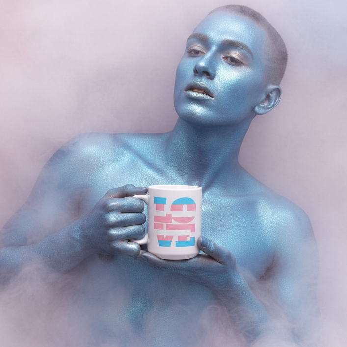 Androgynous model painted metallic blue holds the Transgender Love Mug, featuring bold pink and blue CHILLA graphics