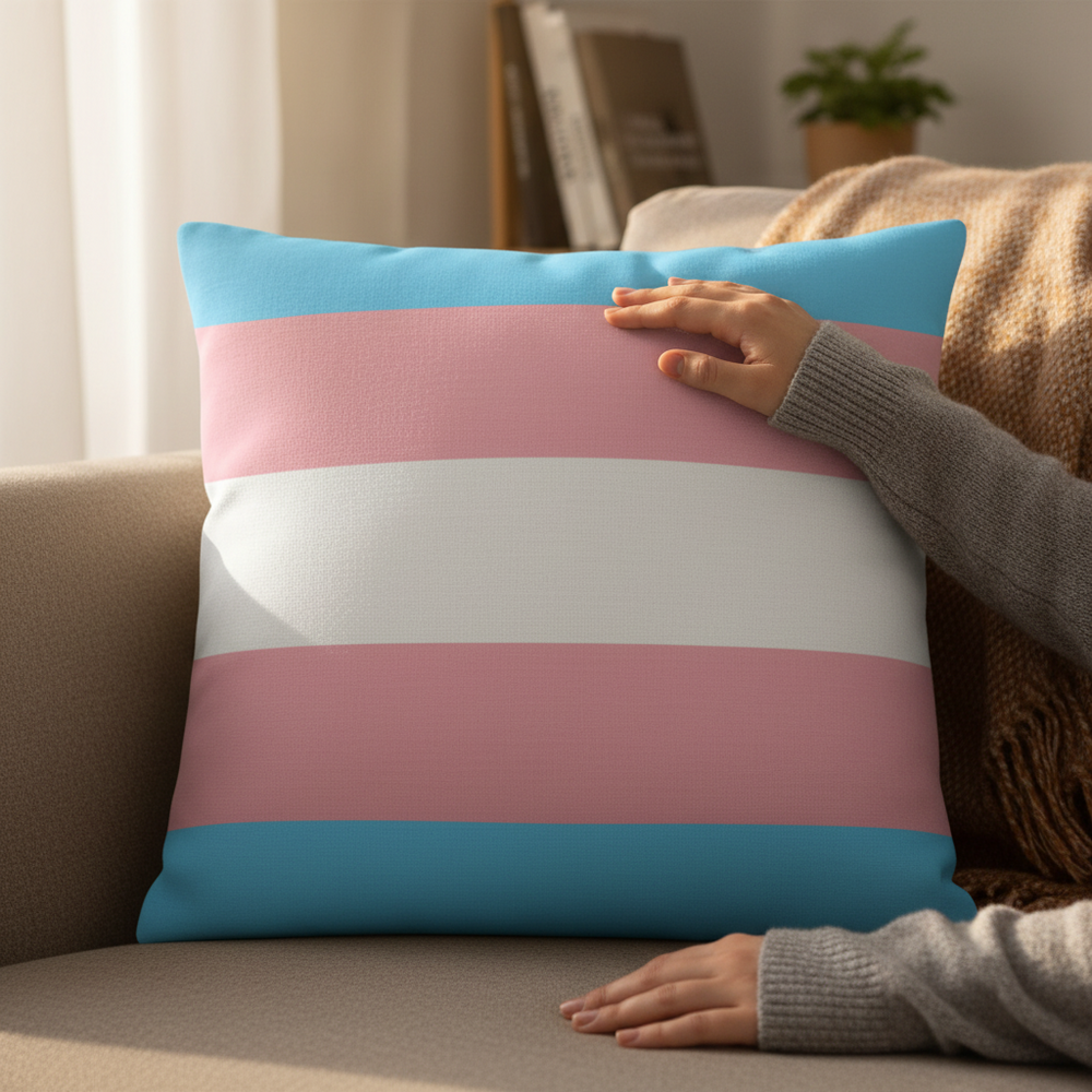 A hand touches a Transgender Premium Pillow with light blue, pink, and white stripes on a beige couch