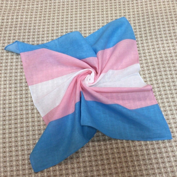 Transgender pride bandana twisted into a spiral on a textured beige surface