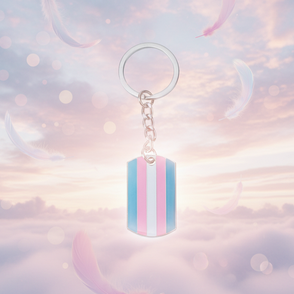 Transgender Pride keychain with a striped dog-tag pendant, photographed against a pastel sky